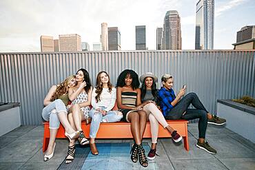 A group of young women partying on a city rooftop at dusk