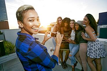 A group of young women partying on a city rooftop at dusk