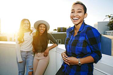 Three young women on a rooftop at dusk