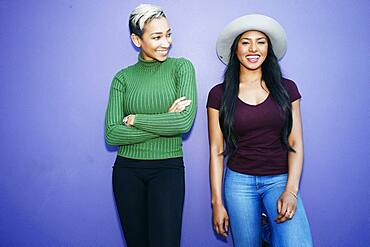 Two young women standing side by side against a plain background