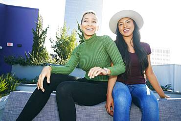 Two young women on a rooftop posing for photographs