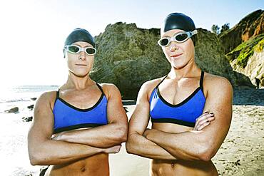 Two sisters, triathletes in training in swimwear, swimhats and goggles.