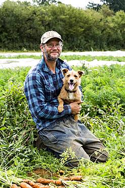 Farmer holding bunch of freshly picked carrots.