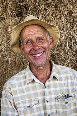 Smiling man wearing sun hat, looking at camera.