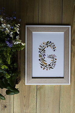 Floral letter G in wooden frame, decorations for a woodland naming ceremony.