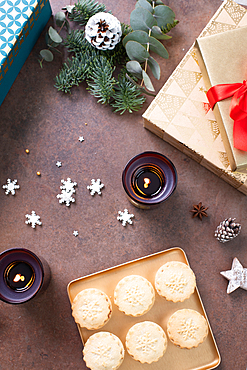 Christmas, overhead view of mince pies on a plate and star shapes and lit candles.