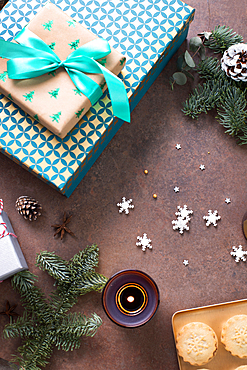 Christmas, overhead view of gifts, mince pies on a plate and lit candles.