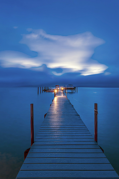 Jetty dock onto ocean at dawn with dramatic sky above.