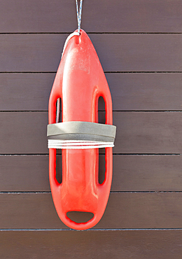 Orange lifeguard buoy, a safety float hanging on a wood wall