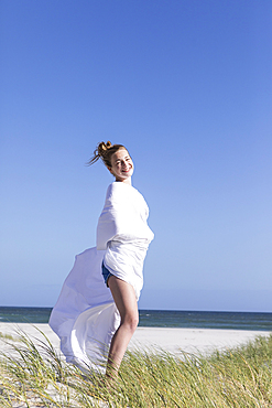 Teenage girl wrapped in white, Grotto Beach, Hermanus, Western Cape, South Africa.