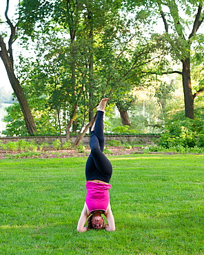 Woman balancing in yoga pose in park.