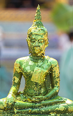 Buddha statue with gold leaf flaking at the Grand Palace Bangkok, Thailand