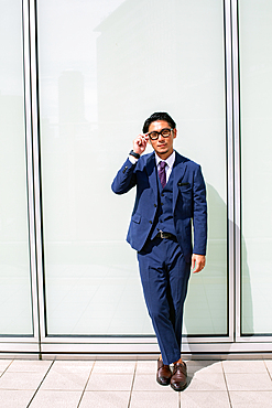 A young businessman in the city, on the move, a man in a smart blue suit.