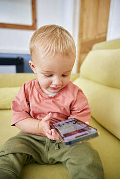 Toddler looking at smart phone indoors