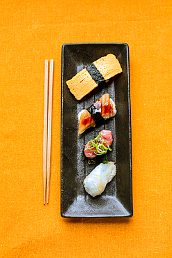 Sushi platter, a selection of raw fish and rice snacks with chopsticks.