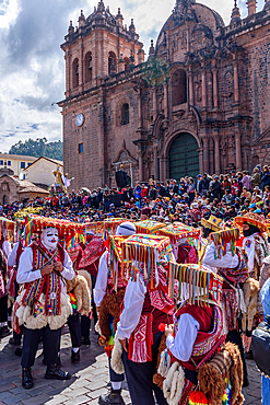 Cusco, a cultural fiesta, people dressed in traditional colourful costumes with masks and hats, brightly coloured streamers, in the Cusco central square by the cathedral.