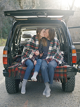 Young couple sitting in the back of their car, kissing, Millcreek, Utah, United States of America