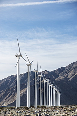 Wind power turbines in the landscape. A large number of turbine powers on a plain against a mountain backdrop, United States of America