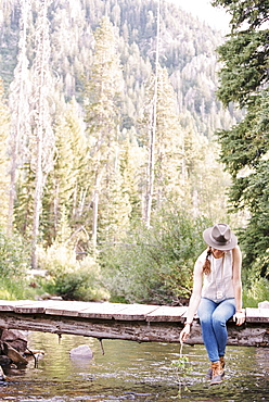 Woman sitting on a wooden bridge over a stream.