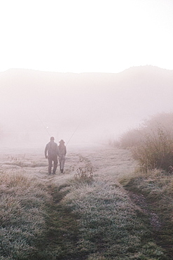 Two people, a man and woman walking along a path on a frosty morning.