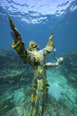 A young woman snorkels near the Christ of the Abyss Statue, Key Largo, Florida Keys.  The bronze statue was submerged in the waters of Key Largo, Florida in 1965.