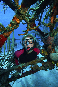 Snorkeler framed by the struts of a wreck of a plane on the seabed.