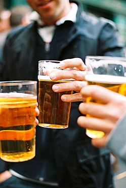 Three people drinking beer. Toasting each other.