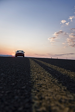 Low angle view looking up at a convertible sports car on the road at sunset, United States of America