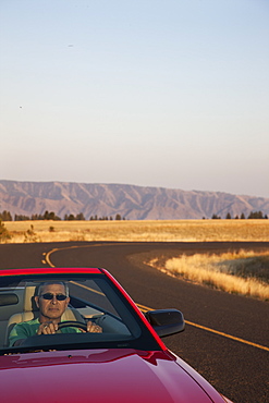 A senior Hispanic man at the wheel of his convertible sports car, United States of America