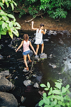 Girls using stones to cross creek, United States of America