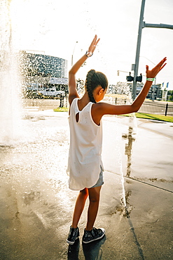 Girl playing in public fountain in summer, United States of America