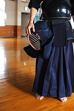 Male Japanese Kendo fighter standing in a gym, holding Kendo mask, Kyushu, Japan