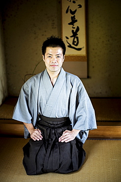 Japanese man wearing kimono sitting on floor in traditional Japanese house, looking at camera, Kyushu, Japan