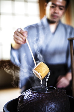 Close up of traditional Japanese Tea Ceremony, man using a Hishaku, a bamboo ladle, to pour hot water, Kyushu, Japan