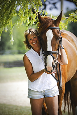 A woman standing next to a bay horse with a halter rein, England