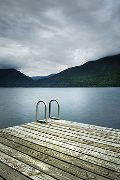 Ladder on wooden pier near still remote lake