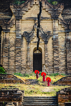 Asian monks standing under umbrellas near historic temple, Mingun, Mandala, Myanmar