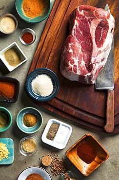 Cutting board with pork shoulder and variety of spices, Seattle, Washington, USA