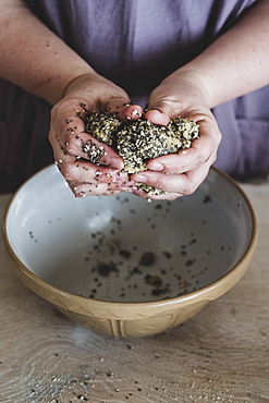 High angle close up of person kneading dough over mixing bowl, England