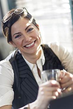 A woman holding a glass and smiling at the camera. A working lunch, New Hope, Pennsylvania, USA