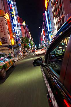 Motion blurred view from taxi of street and neon advertising signs at night in Shinjuku District, Tokyo, Japan