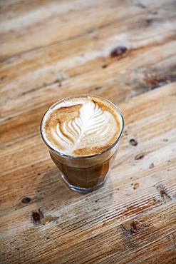 High angle close up of glass of cafe latte on a wooden table