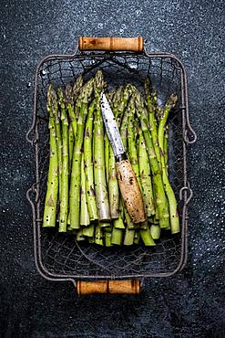 High angle close up of freshly picked green asparagus in metal basket