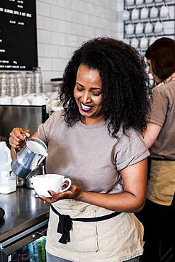 Woman barista preparing a cup of coffee in a coffee shop