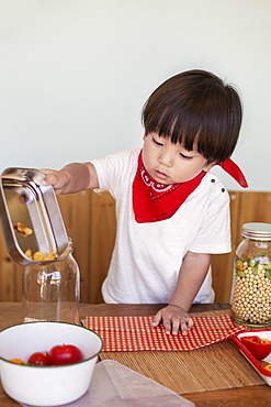 Japanese boy standing at a table in a farm shop, helping prepare food, Kyushu, Japan