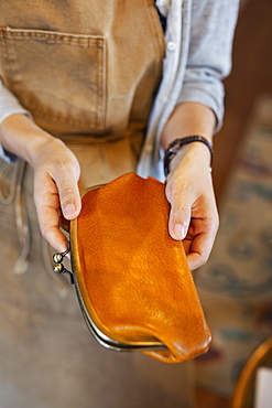 High angle close up of person standing in a leather shop, holding an leather purse, Kyushu, Japan