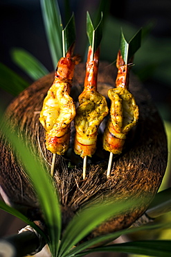 High angle close up of charcoal-grilled prawn satay on a coconut shell, Thailand