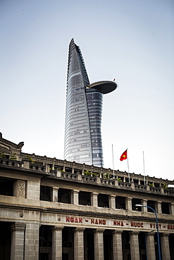 Facade of historic stone building with contemporary skyscraper in the background, Vietnam