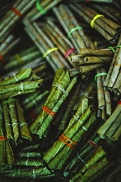 High angle close up bundles of beedi cigarettes, tobacco wrapped in green leaves and tied with a string, India