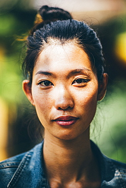 Portrait of a young woman with black hair tied in a top knot, looking at camera, Vietnam